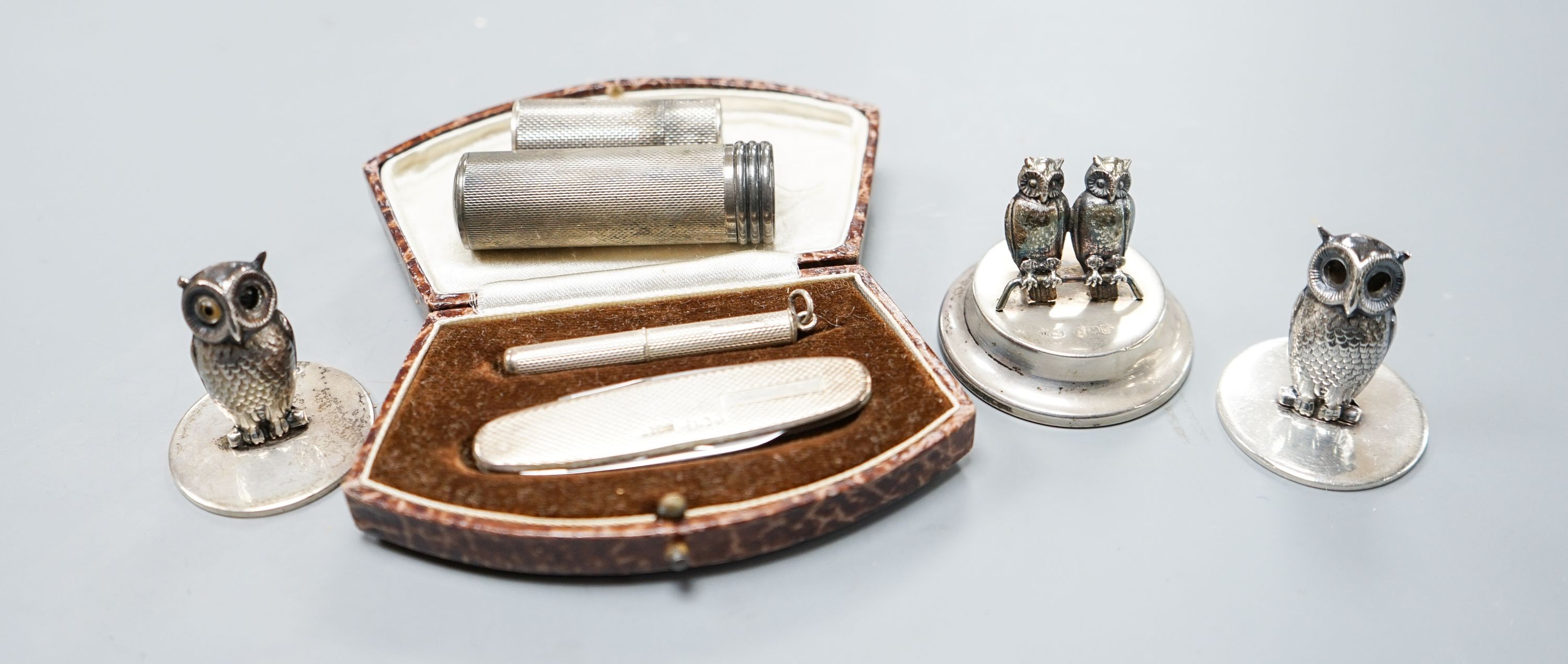 Three silver 'owl' menu holders, including a pair by Samson Mordan & Co, London, 1926, 30mm an engine-turned silver penknife and toothpick set (cased) and two silver cylindrical containers.
